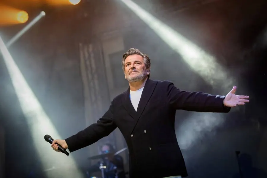 Thomas Anders s rozpaženýma rukama na pódiu během koncertu